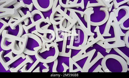 random white wooden alphabet letters top view on purple background Stock Photo