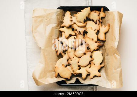 Pile of Christmas-themed gingerbread cookies on baking tray. Stock Photo