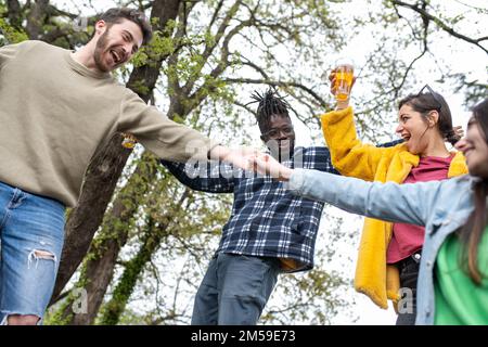 Diverse people having fun, friends enjoying happy times outdoor, multiracial team dancing and laughing in nature Stock Photo