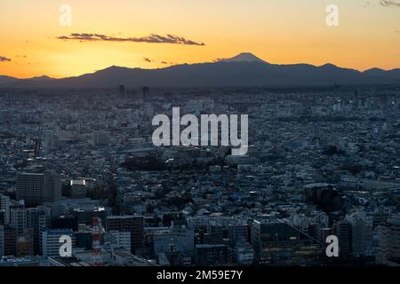 Tokyo, Japan. 26th Dec, 2022. The sun sets over Mt. Fuji (å¯Œå£«å±±), an active stratovolcano along the Pacific Ocean Ring of Fire which last erupted over 300 years ago with Tokyo and the manufacturing industrial city of Kawasaki in the foreground. Also known as Fujisan, the volcano is admired for it's beauty and is a major tourist and hiking destination. The center of Tokyo is approximately 100 kilometers from Mt. Fuji and the mountain is the seventh-highest peak of an island on Earth.Japan has recently reopened to tourism after over two years of travel bans due to the COVID-19 pandemic. Stock Photo