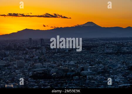 Tokyo, Japan. 26th Dec, 2022. The sun sets over Mt. Fuji (å¯Œå£«å±±), an active stratovolcano along the Pacific Ocean Ring of Fire which last erupted over 300 years ago with Tokyo and the manufacturing industrial city of Kawasaki in the foreground. Also known as Fujisan, the volcano is admired for it's beauty and is a major tourist and hiking destination. The center of Tokyo is approximately 100 kilometers from Mt. Fuji and the mountain is the seventh-highest peak of an island on Earth.Japan has recently reopened to tourism after over two years of travel bans due to the COVID-19 pandemic. Stock Photo