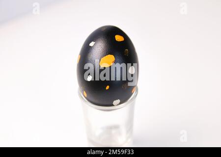 Defocus one black egg with orange and white dots. Close up Easter egg on white background. Minimal Easter celebration concept. Balance harmony concept Stock Photo