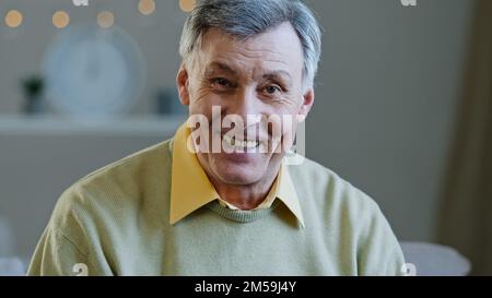 Happy elderly middle aged man make video call recording vlog remotely communicate in online chat senior 60s grandpa smiling wave hand looking at Stock Photo
