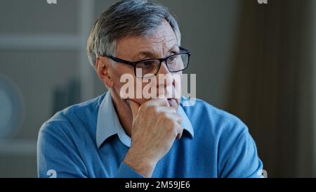 Portrait indoor in office home old thoughtful pensive confused senior man feel worried think memory problem take off glasses forgotten information Stock Photo