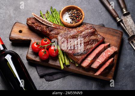 Medium rare grilled Tomahawk beef steak with asparagus Stock Photo