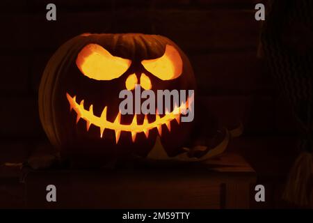 Spooky Halloween pumpkin, Jack O Lantern with pumpkins lights hanging from a window during a party Stock Photo