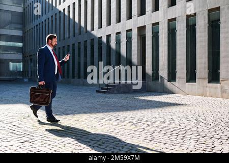 Businessman using the mobile while walking in the street Stock Photo