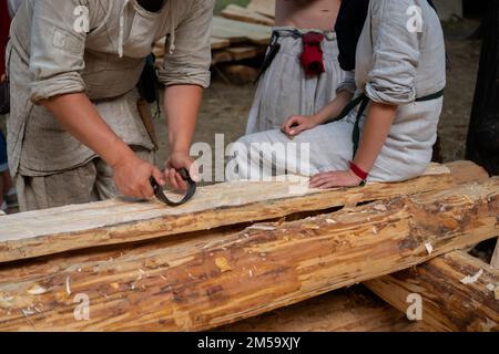 Man carpenter using drawknife to shape and smooth wood board Stock Photo