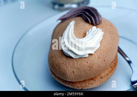 dessert, small oval cake , pastry with cocoa and vanilla fill on a plate. Stock Photo