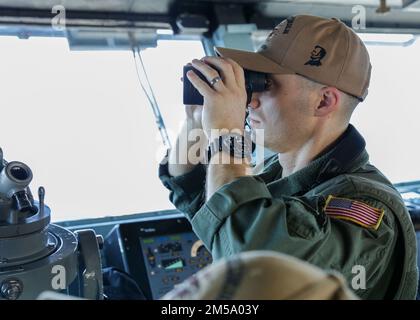 PHILIPPINE SEA (Feb. 13, 2022) U.S. Navy Lt. Matt Little, assistant navigator of the Nimitz-class aircraft carrier USS Abraham Lincoln (CVN 72), observes flight operations in support of Jungle Warfare Exercise 22 (JWX 22) across Okinawa, Japan, Feb. 13, 2022. JWX 22 is a large-scale field training exercise focused on leveraging the integrated capabilities of joint and allied partners to strengthen all-domain awareness, maneuver, and fires across a distributed maritime environment. Stock Photo