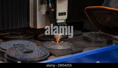 CNC laser cutting machine cutting holes on metal workpiece in factory. Industrial manufacture. Stock Photo