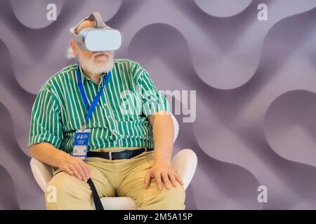 Elderly man using virtual reality headset at VR exhibition Stock Photo