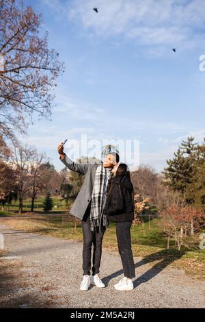 Man and woman posing in the park. Multiracial couple in love taking selfy photos. Stock Photo