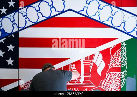 Members of Task Force Liberty work with guests to paint a mural depicting the journey of the Afghans resettlement from Afghanistan to the United States, while at Joint Base McGuire-Dix-Lakehurst, New Jersey, Feb. 14, 2022. The Department of Defense, through U.S. Northern Command, and in support of the Department of Homeland Security, is providing transportation, temporary housing, medical screening, and general support for at least 11,000 Afghan evacuees at Liberty Village, in permanent or temporary structures, as quickly as possible. This initiative provides Afghan personnel essential support Stock Photo