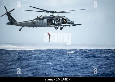 A U.S. Air Force pararescueman with the 31st Rescue Squadron jumps out of an HH-60G Pave Hawk from the 33rd Rescue Squadron during exercise Cope North 22 at the Island of Tinian near Andersen Air Force Base, Guam, Feb. 14, 2022. Japanese and U.S. Air Force members trained together in participation of Cope North 2022, multilateral U.S. Pacific Air Forces-sponsored field training exercise conducted annually at Andersen AFB, Guam focused on combat air forces’ large-force employment and humanitarian assistance and disaster relief training to enhance interoperability among U.S., Australian, and Jap Stock Photo