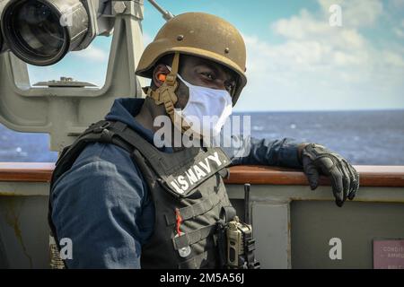 Culinary Specialist Seaman Kelvin Adjei, from New York, NY, participates in a gun exercise aboard the guided-missile destroyer USS Momsen (DDG 92) while underway in the Pacific Ocean, February 14, 2022. USS Momsen is currently deployed in U.S. 3rd Fleet area of operations. Stock Photo