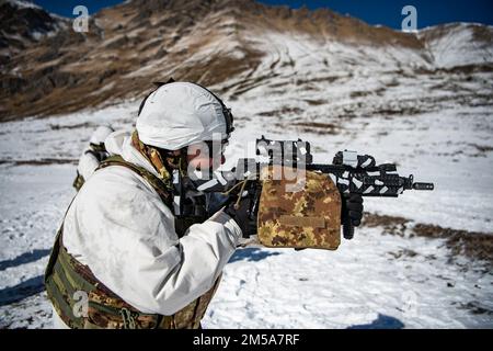 An Italian soldier from the 3rd Alpini Regiment provides covering fire for his team during an integrated marksmanship range alongside U.S. Army paratroopers assigned to the 173rd Airborne Brigade. This training is part of Exercise Steel Blizzard at Pian dell’Alpe in Usseaux, Italy on Feb. 15, 2022.     Exercise Steel Blizzard is an Italian Army-hosted multinational mountain and arctic warfare training exercise. Three reconnaissance platoons from the 173rd Airborne Brigade take part in a three-phase training regimen with the 3rd Alpini Regiment to expand force capabilities by learning how to sh Stock Photo