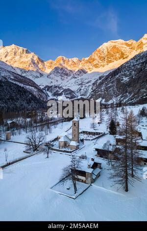 Sunrise in front of Monte Rosa from the old church of Macugnaga in winter. Valle Anzasca, Ossola, province of Verbania, Piedmont, italian alps, Italy. Stock Photo