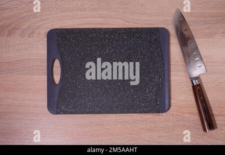 Empty plastic black board and kitchen knife on the table, top view Stock Photo