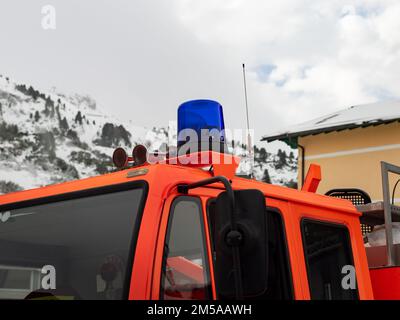 Blue rotating beacon light on an orange fire engine. Rooftop of a fire-fighting truck in close-up view. The silver truck horn warns people. Stock Photo
