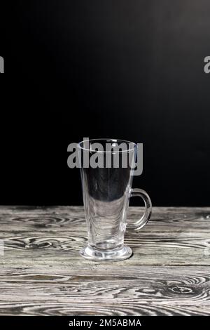 Empty glass goblet. Stands on black pine boards. On a black background. Stock Photo