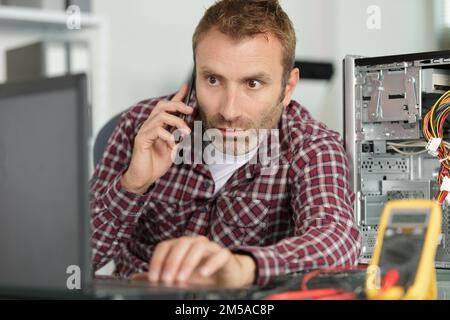 technician repairing a computer and phone to the customer Stock Photo