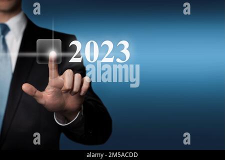 New Year 2023 - finger pressing virtual touchscreen button Stock Photo