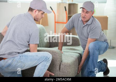 two handsome smiling movers carrying a sofa Stock Photo
