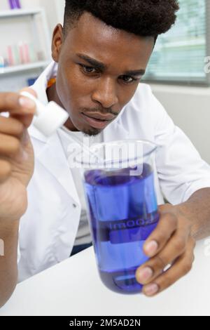 young man scientist using auto-pipette with flask in laboratory Stock Photo