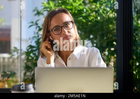 Cheerful mature businesswoman working from cafe, having online video call using laptop.  Stock Photo