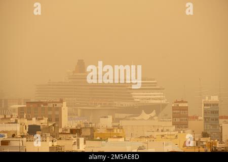 Las Palmas, Gran Canaria, Canary Islands, Spain. 27th December 2022. Eerie light on the city beach in Las Palmas as Saharan sand and dust blowing in on strong winds from Africa reduces visibility. PICTURED: Cunard line cruise ship, Queen Victoria in Las Palmas as Saharan dust and sand reduces visibility. Credit: Alan Dawson/Alamy Live News Stock Photo