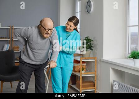Young nurse helping a senior patient to walk with his crutches. Stock Photo