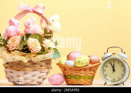 Easter composition still life. Baskets with roses and eggs alarm clock on the table. Stock Photo