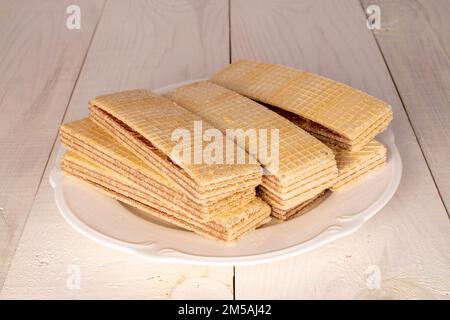 Several sweet chocolate wafers with white plate  on wooden table, close-up. Stock Photo