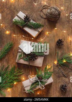 Christmas presents wrapped in craft paper with natural fir tree and thuja branches as decoration. Top view on wooden table with New Year gifts Stock Photo