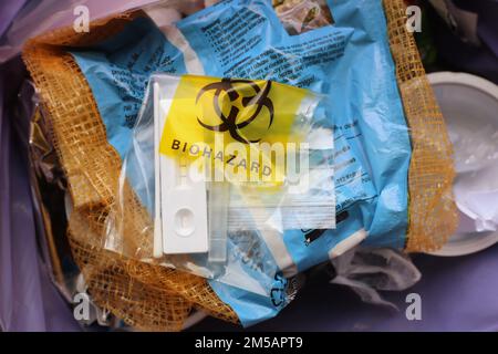 Used SARS Covid antigen test kit in the biohazard disposable bag thrown into a garbage can. Stock Photo