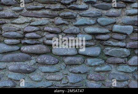 Background of an old stone wall made out of large rocks which look purple, pink and magenta coloured Stock Photo