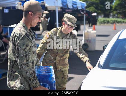 HONOLULU, Hawaii (Feb. 17, 2022) – U.S. Navy Electronics Technician (Nuclear) 1st Class Andrew Loera, assigned to Naval Sea Systems Command, and U.S. Army Spc. Lyndsee Fielding, assigned to the 57th Military Police Company, 728th Military Police Battalion, 8th Military Police Brigade, hand out water at the Navy Exchange Moanalua Terrace water distribution station. U.S. Navy is working closely with the Hawaii Department of Health, U.S. Environmental Protection Agency and the U.S. Army to restore safe drinking water to Joint Base Pearl Harbor-Hickam housing communities through sampling and flush Stock Photo