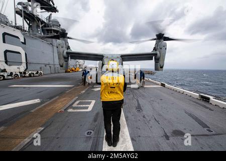 PHILIPPINE SEA (Feb. 17, 2022) Aviation Boatswain’s Mate (Handling) 2nd Class Robert Wynn, center, from Apopka, Fla., assigned to the forward-deployed amphibious assault ship USS America (LHA 6), readies an MV-22B Osprey tiltrotor aircraft from the 31st Marine Expeditionary Unit (MEU) for take-off on the ship’s flight deck. America, lead ship of the America Amphibious Ready Group, along with the 31st MEU, is operating in the U.S. 7th Fleet area of responsibility to enhance interoperability with allies and partners and serve as a ready response force to defend peace and stability in the Indo-Pa Stock Photo