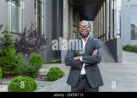 Successful african american boss with arms crossed smiling and looking at camera mature man outside office building. Stock Photo