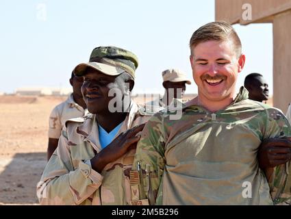 U.S. Air Force Staff Sgt. Tyler Parker, 409th Expeditionary Security Forces Squadron air advisor laughs at a joke from a Niger Armed Forces (French language: Forces Armées Nigeriennes) member during a training event at Nigerien Air Base 201, Agadez, Niger, Feb. 17, 2022. The training included detaining, handcuffing, individual and vehicle searches to help strengthen FAN defense capabilities in support of a more secure, stable Africa. Stock Photo