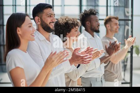 Group of businesspeople sitting in a line and applauding. Stock Photo