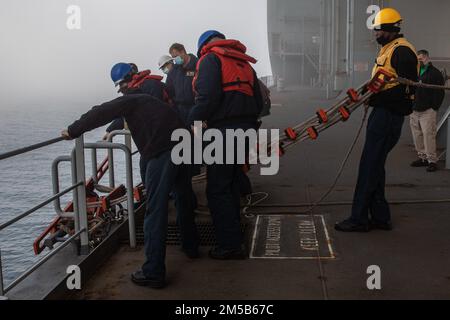 Sailors hoist a small boat aboard the guided-missile destroyer USS ...