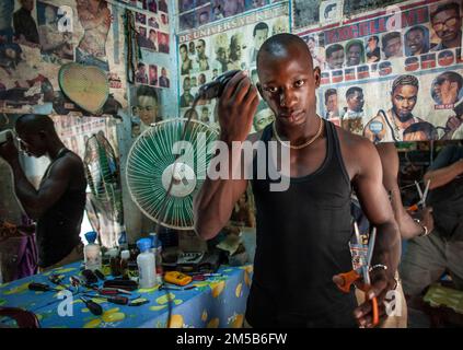Barber with clipper machine in his barber shop in Bamako , Mali , West Africa . Stock Photo