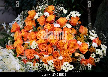 a large bouquet of orang colored roses on a grave after a funeral Stock Photo