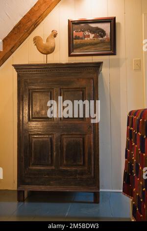 Small wooden armoire and hand railing covered with blanket in hallway on upstairs floor inside  old 1722 French regime style home. Stock Photo