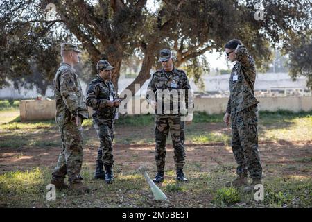 U.S. Marine Corps Sgt. Nicholas Greenisen, an explosive ordnance disposal technician with 2nd Marine Logistics Group, right, explains a training scenario to U.S. Air National Guard Tech. Sgt. Micheal McConnell, a Arabic linguist with the Uthan Air National Guard, left, who helps translate to Royal Moroccan Armed Forces (FAR) soldiers during an instructor training practical application class near Kenitra, Morocco, Feb. 21, 2022. Marines, Sailors, and members of the Utah National Guard are participating in Humanitarian Mine Action, Explosive Ordnance Disposal (EOD) Morocco 2022 where U.S. EOD te Stock Photo