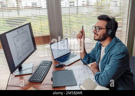 indian male designer in headphones works in home office drawing on graphic tablet Stock Photo