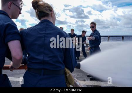 PACIFIC OCEAN (Feb. 23, 2022) Hull Maintenance Technician 1st Class Corinne Gharineh, a native of Anaheim, Calif., instructs Sailors how to operate fire hoses during a damage control training evolution aboard Harpers Ferry-class amphibious dock landing ship USS Pearl Harbor (LSD 52), in the Pacific Ocean, Feb. 23, 2022. Sailors and Marines of the Essex Amphibious Ready Group (ARG) and the 11th Marine Expeditionary Unit (MEU) are underway conducting routine operations in the U.S. 3rd Fleet. Stock Photo