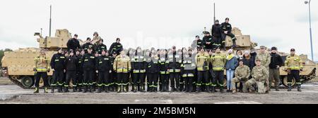 Polish firefighters pose with U.S. Soldiers in front of various military vehicles at the end of their tour at Drawsko Pomorskie, Poland Feb. 23, 2022. Soldiers showed Polish firefighter cadets and instructors various pieces of equipment that they would use as army firefighters in a show of interoperability with the host nation. Stock Photo